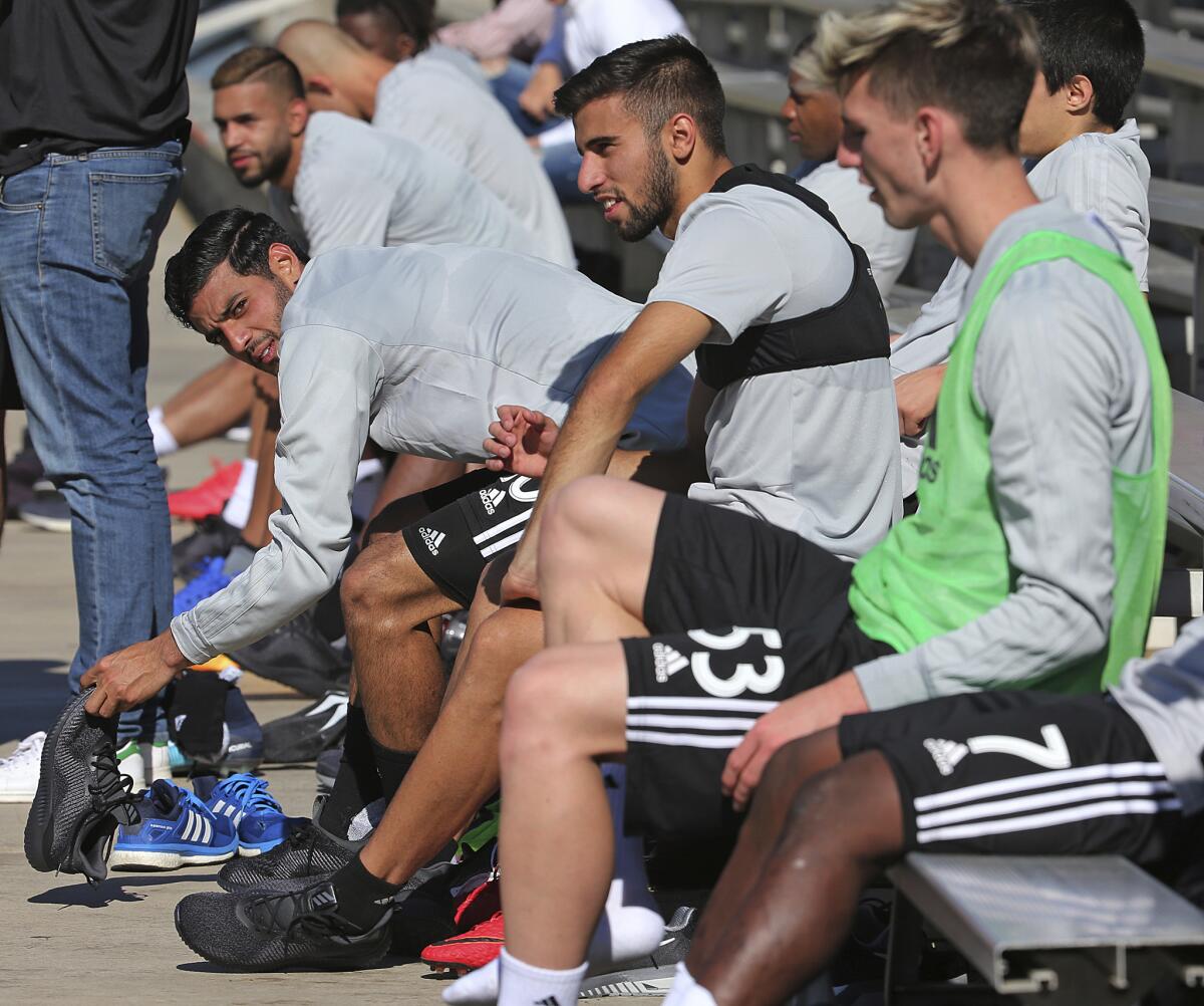 Carlos Vela, left, and Diego Rossi, center, sit on the bench after practice during the introduction of players and coaches at the first training camp of the Los Angeles Football Club soccer team on the campus of UCLA in Los Angeles Monday, Jan. 22, 2018. (AP Photo/Reed Saxon)