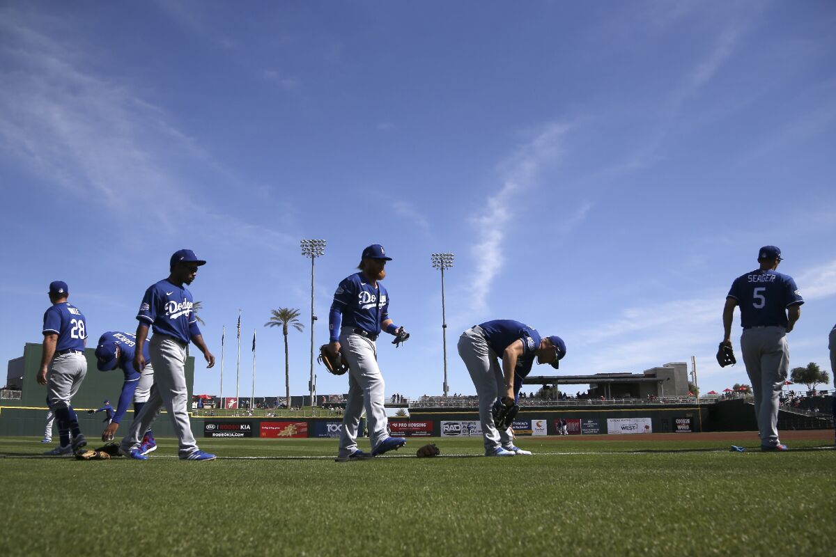 Dodgers players warm up prior to a spring training game against the Cleveland Indians on Feb. 27 in Goodyear, Ariz.