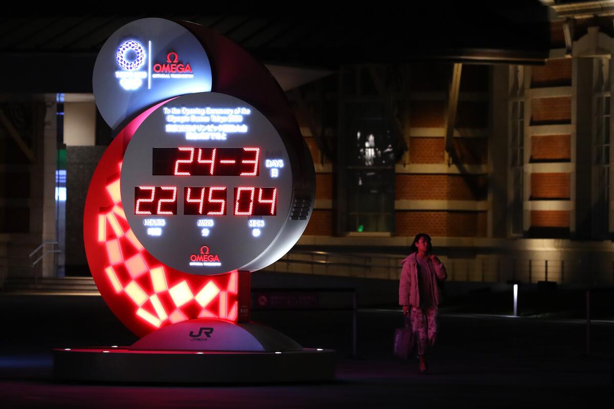TOKYO, JAPAN - MARCH 24: People watch the official Olympic countdown clock with the remaining days and time until the 2020 Summer Olympics after it was announced that they will be postponed until 2021 due to the coronavirus outbreak, on March 24, 2020 in Tokyo, Japan. The 2020 Summer Olympic Games in Tokyo are to be postponed until 2021 after talks between Japan’s prime minister, Shinzo Abe, and the International Olympic Committee president, Thomas Bach. The Coronavirus (COVID-19) pandemic has spread to at least 182 countries, claiming over 17,000 lives and infecting hundreds of thousands more. (Photo by Clive Rose/Getty Images)