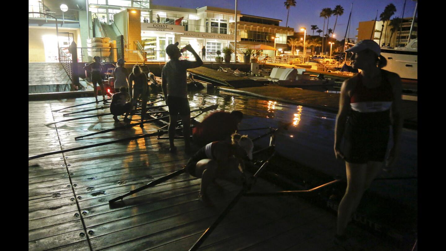 Team members of the Newport Sea Base Rowing Club gather before sunrise to launch their boats in Newport Harbor. Rowing, which includes sweep boats that use single-sided oars and sculls with double oars, has solo and two-man boats but is overwhelmingly a team sport.