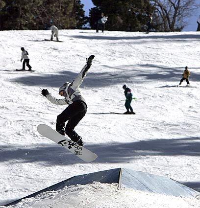 A snowboarder takes flight as a lone skier makes their way down the mountain with other snowboarders at Mountain High in Wrightwood Saturday, Feb. 10, 2007.