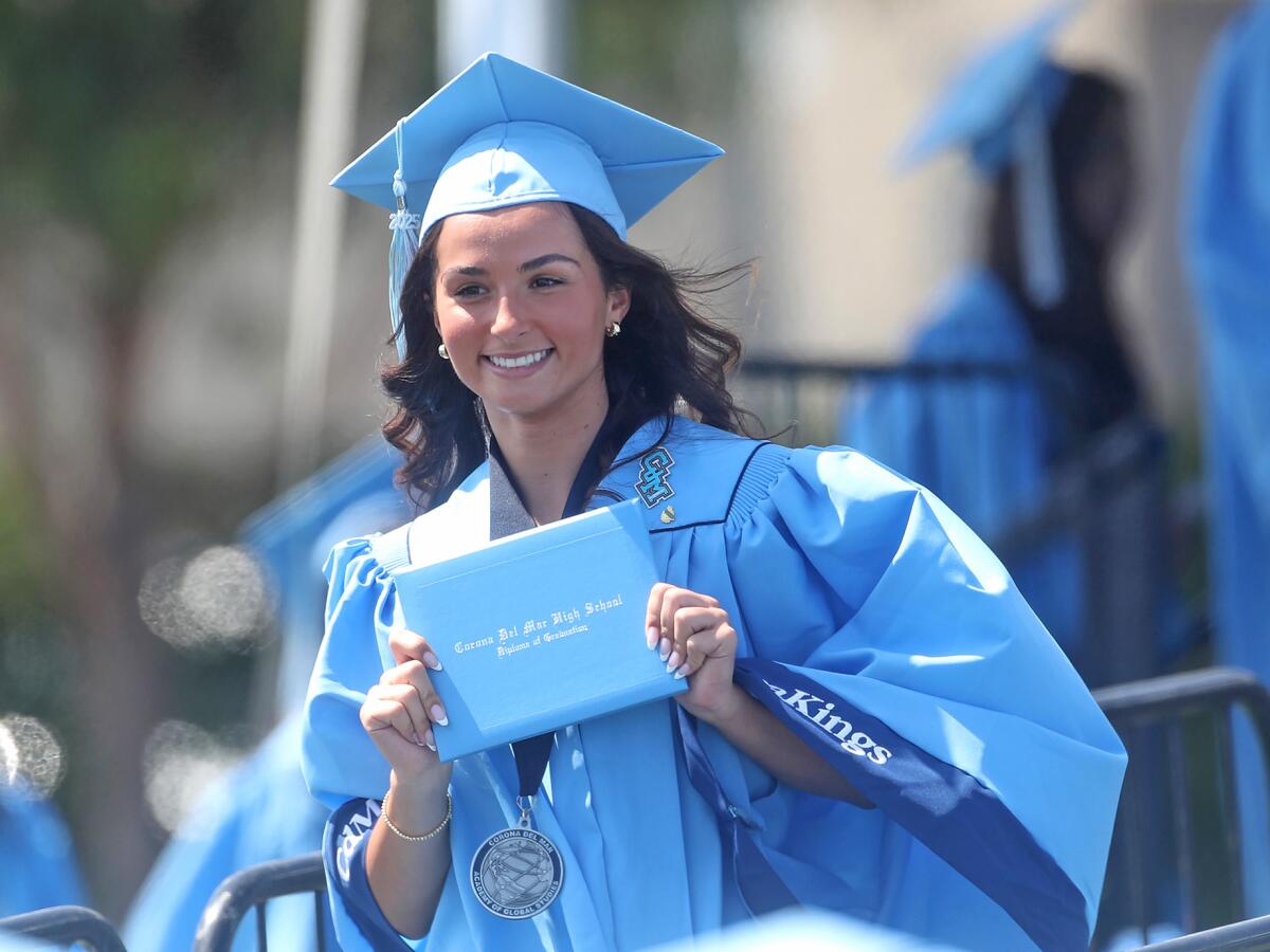 A smiling graduate shows off her diploma.