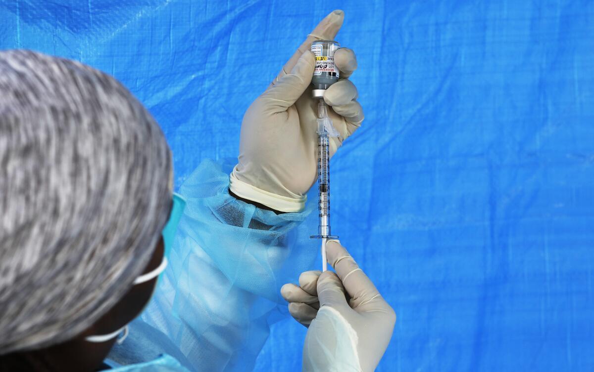 Closeup of gloved hands using a syringe to draw a shot from a vial