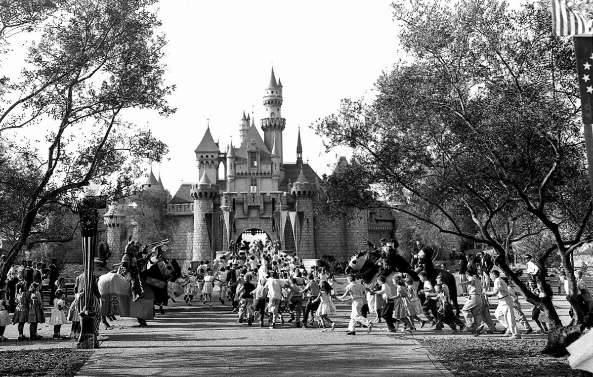 A black-and-white photo of a crowd heading toward a storybook castle