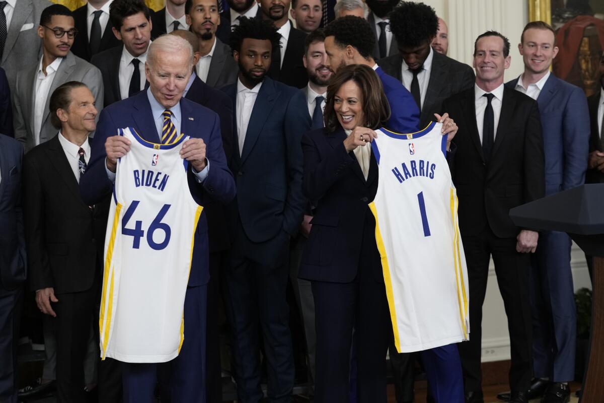 President Joe Biden and Vice President Kamala Harris hold up team jerseys as they welcome the 2022 NBA champions, the Golden State Warriors, to the East Room of the White House in Washington, Tuesday, Jan 17, 2023. (AP Photo/Susan Walsh)