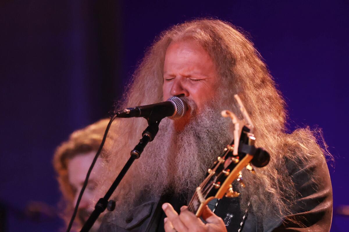 Jamey Johnson sings into a microphone and plays guitar