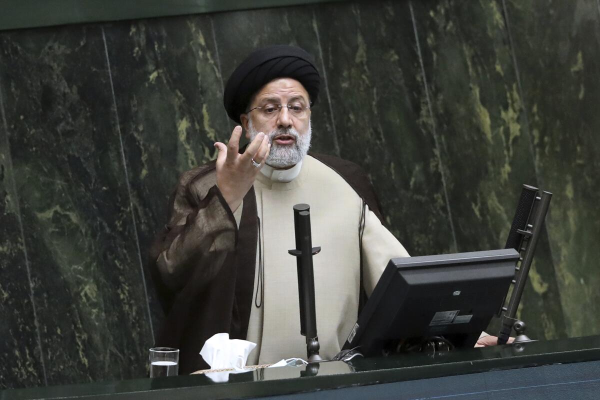 Iranian President Ebrahim Raisi holds up his hand while talking