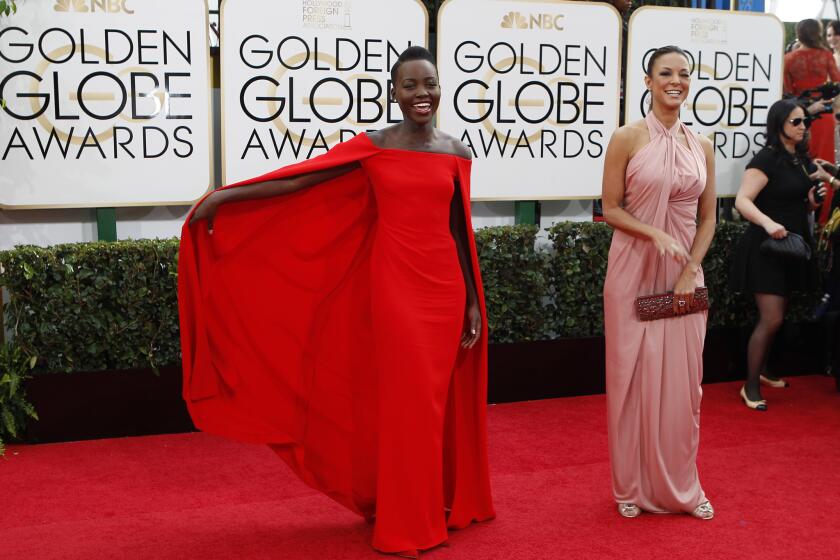 Actress Lupita Nyong'o in a red cape dress by Ralph Lauren.