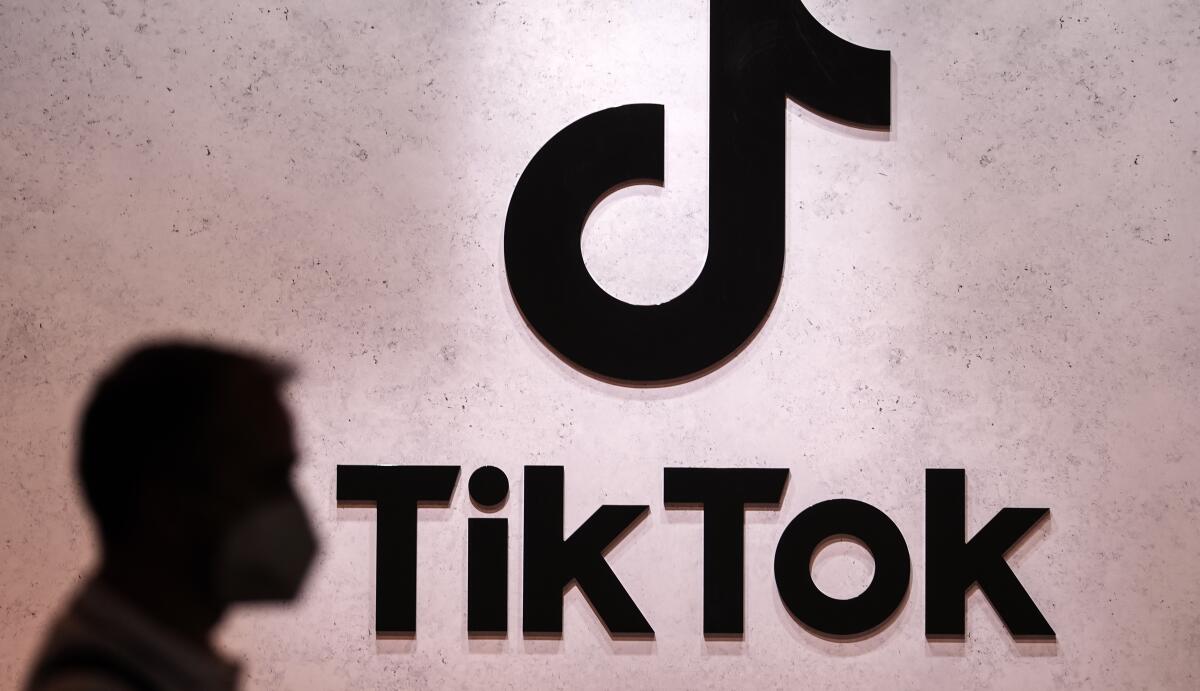 A "TikTok" sign on a wall next to a silhouette of a head.