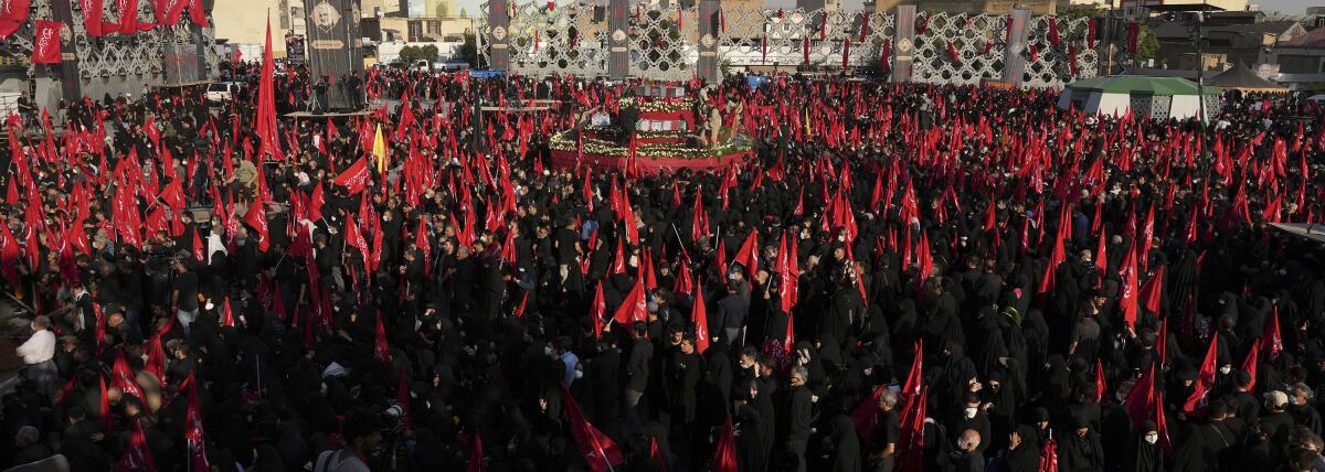 Mourners wave red flags as they gather around flag-draped coffins of five members of Iran's paramilitary Revolutionary Guard killed in Syria, whose remains were recently recovered, during their funeral ceremony in Tehran, Iran, Thursday, Aug. 4, 2022. The thousands that gathered in Tehran's streets on Thursday evening waved red flags to mark Ashoura, a commemoration of the 7th century death of Prophet Muhammad's grandson Hussein, a revered figure in Shiite Islam. (AP Photo/Vahid Salemi)