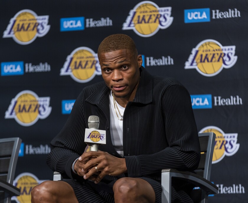 Russell Westbrook leans forward in his chair to answer a question from a reporter.