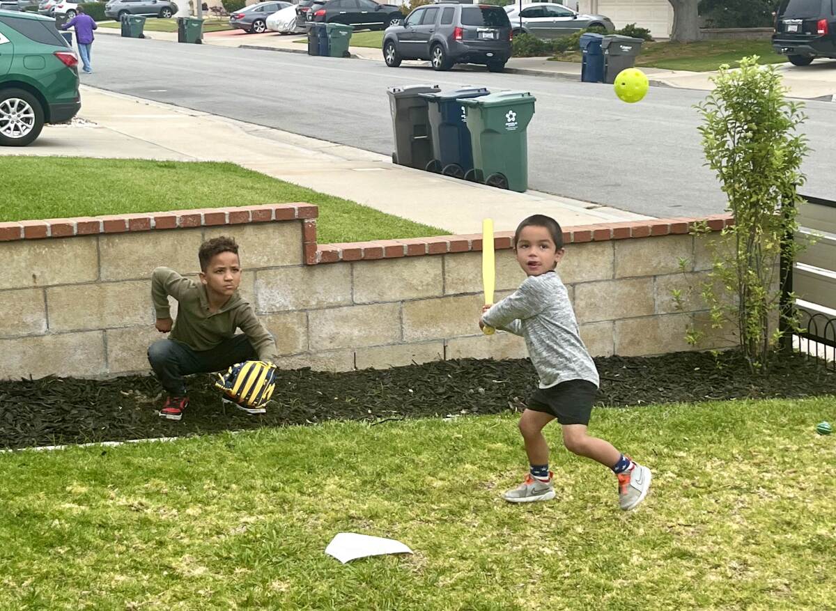 Bentley Knutsen prepares to swing in a game of frontyard wiffle ball as AJ Knutsen catches on Tuesday.