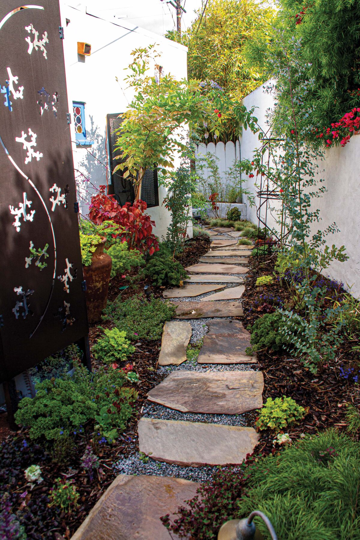 Diverse plantings and a flagstone path beckon visitors into a garden.