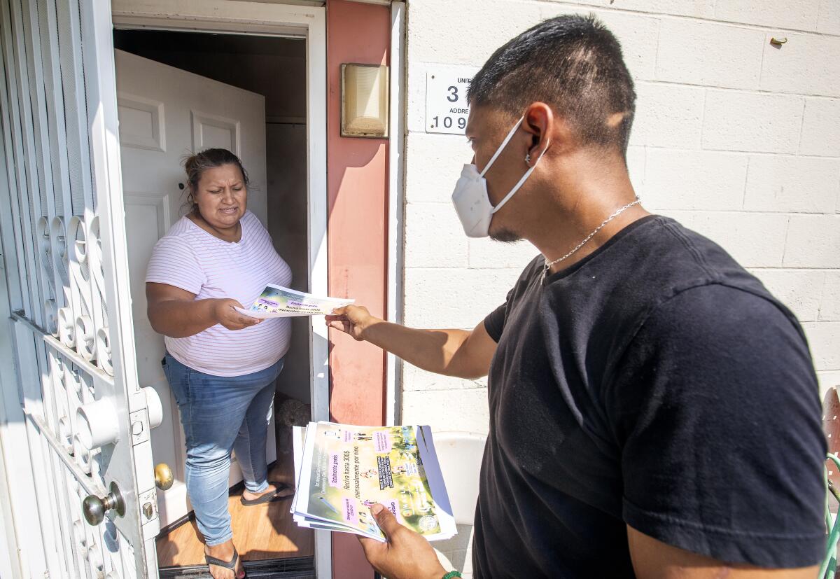 San Fernando Gardens resident Gloria Acosta receives a flier from a volunteer