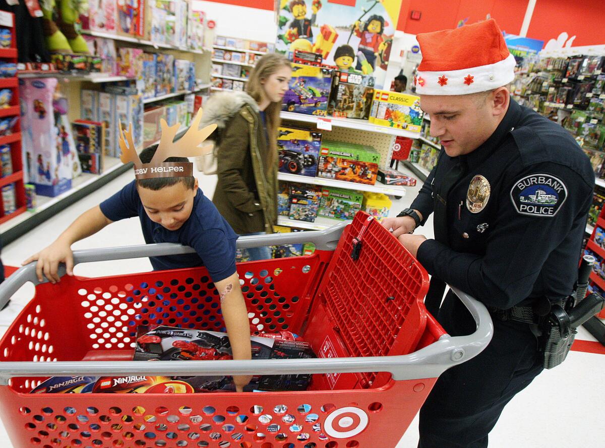 Tyrese Navel, 9, checks out the toys he found as Burbank Police Officer Michael Hounanian pushes the cart at Target for the Burbank Police Department's "Shop with a Cop" event.