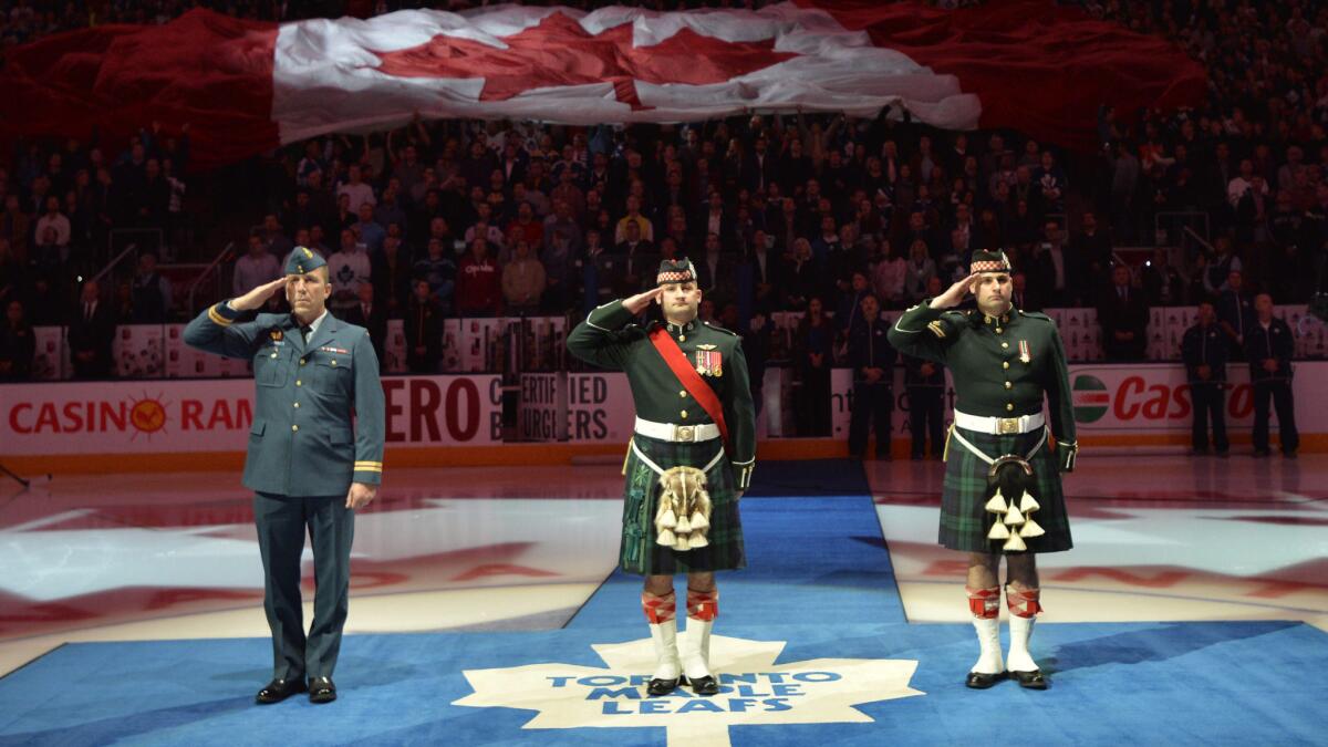 Members of the Canadian Forces salute as they take part in a ceremony honoring two fallen soldiers Saturday before a game between the Toronto Maple Leafs and Boston Bruins.