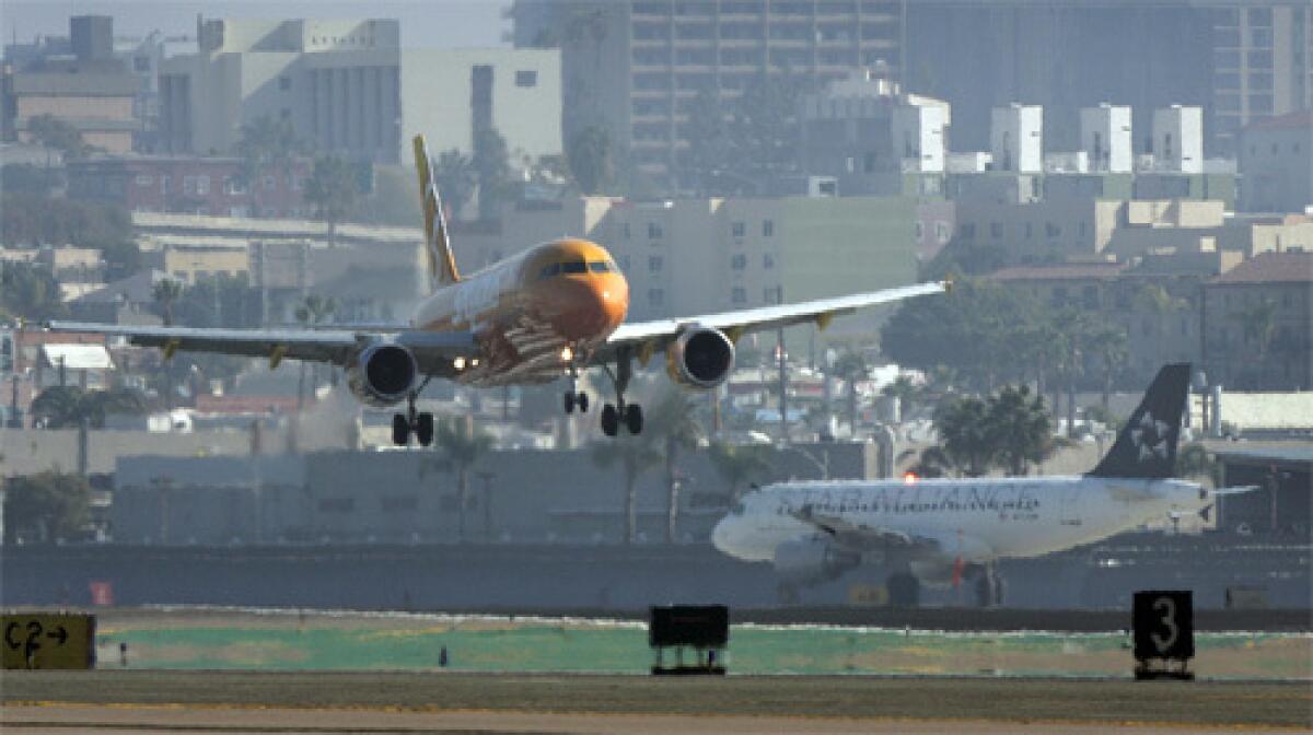 MAKING FLYING SAFER: A plane lands while another taxis at San Diegos Lindbergh Field. A red-light warning system currently being tested at the airfield has reduced the number of close calls on runways and taxiways.