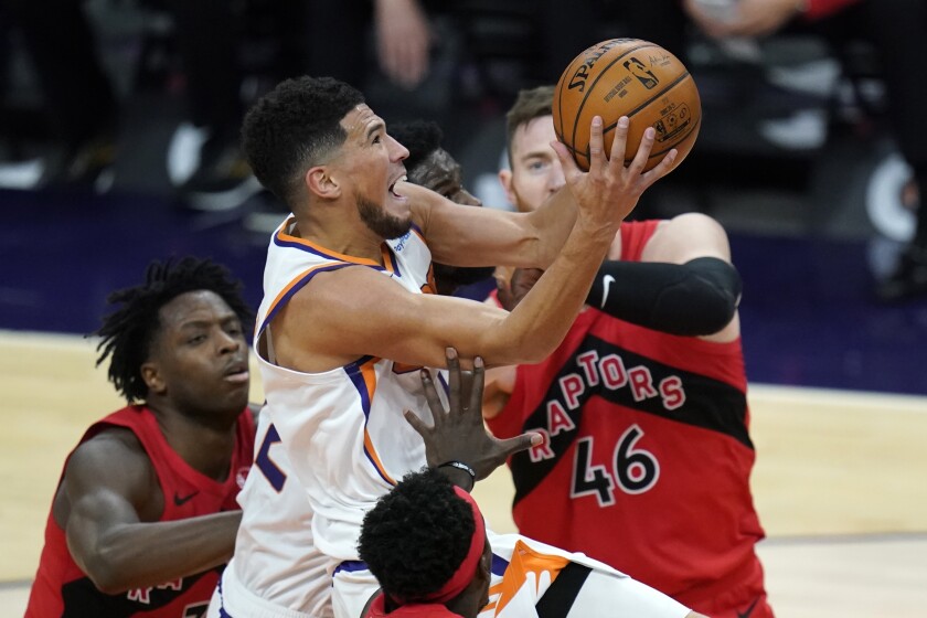 Phoenix Suns guard Devin Booker, middle, drives past Toronto Raptors center Aron Baynes (46) and Raptors forward OG Anunoby, left, during the second half of an NBA basketball game Wednesday, Jan. 6, 2021, in Phoenix. (AP Photo/Ross D. Franklin)