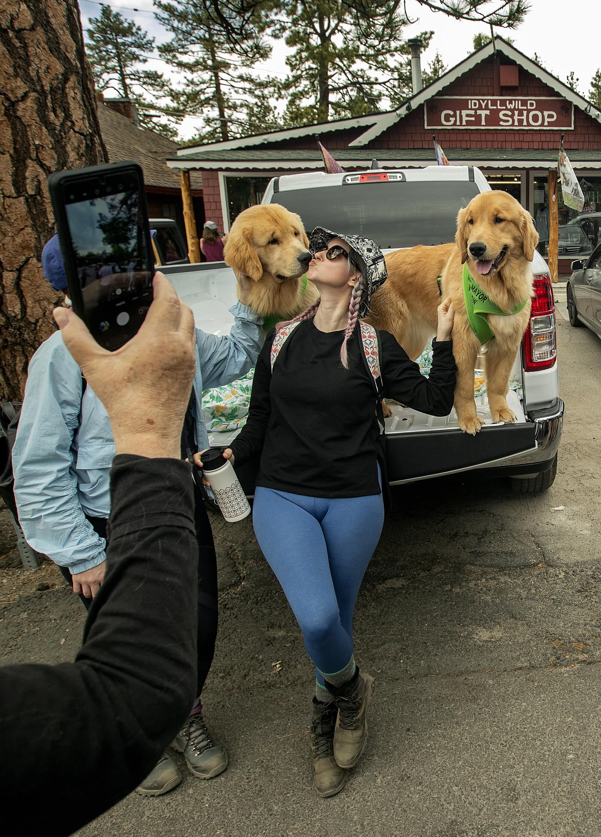 A woman poses with two golden retrievers.