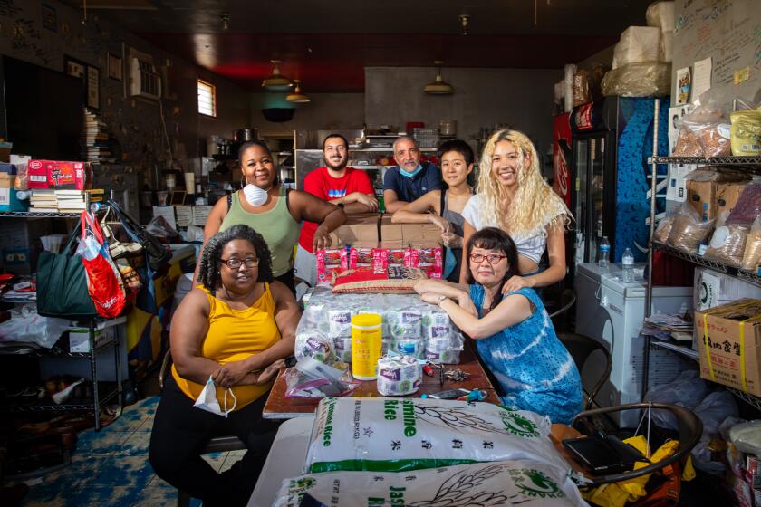 LOS ANGELES, CA - MAY 06: From front left, Zerita Jones (yellow tank), her daughter Zenae Lawrence (green tank), Ziad Shalabi (red shirt), chef Farid Zadi, Brittany Ko (gray tank), Kamilah Zadi (white top, daughter of Zadi and Park) and Susan Ji Young Park, owner of Revolutionario restaurant, pose for a portrait in the Los Angeles, CA, restaurant, Wednesday, May 6, 2020, during the coronavirus pandemic. Jones joined Park in her food bank efforts once the pandemic took over, expanding outreach beyond skid row and the asian community and helping get food and supplies to older black residents of Los Angeles. (Jay L. Clendenin / Los Angeles Times)