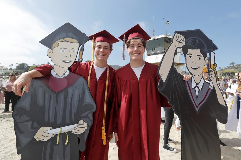 Twin brothers Jack and Sam Arntz stand with life-size cardboard cutouts of themselves on the sand at Main Beach as they participate in the Laguna Beach High Class of 2022 Parade down Ocean Ave. on Wednesday.