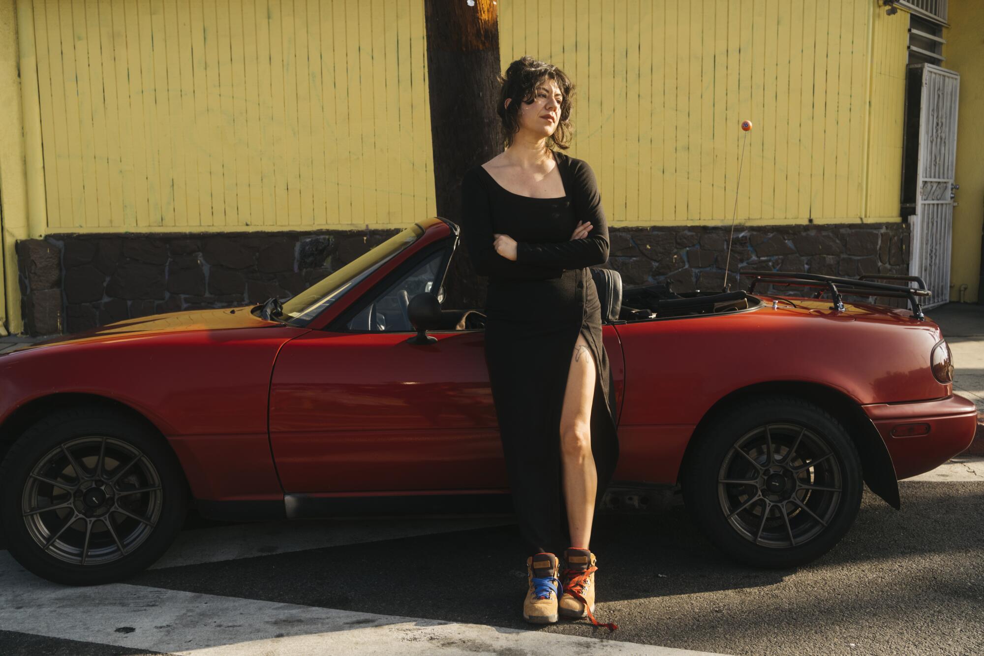 Christina Catherine Martinez, a comedian, writer, and art critic, poses for a portrait with her Mazda Miata.