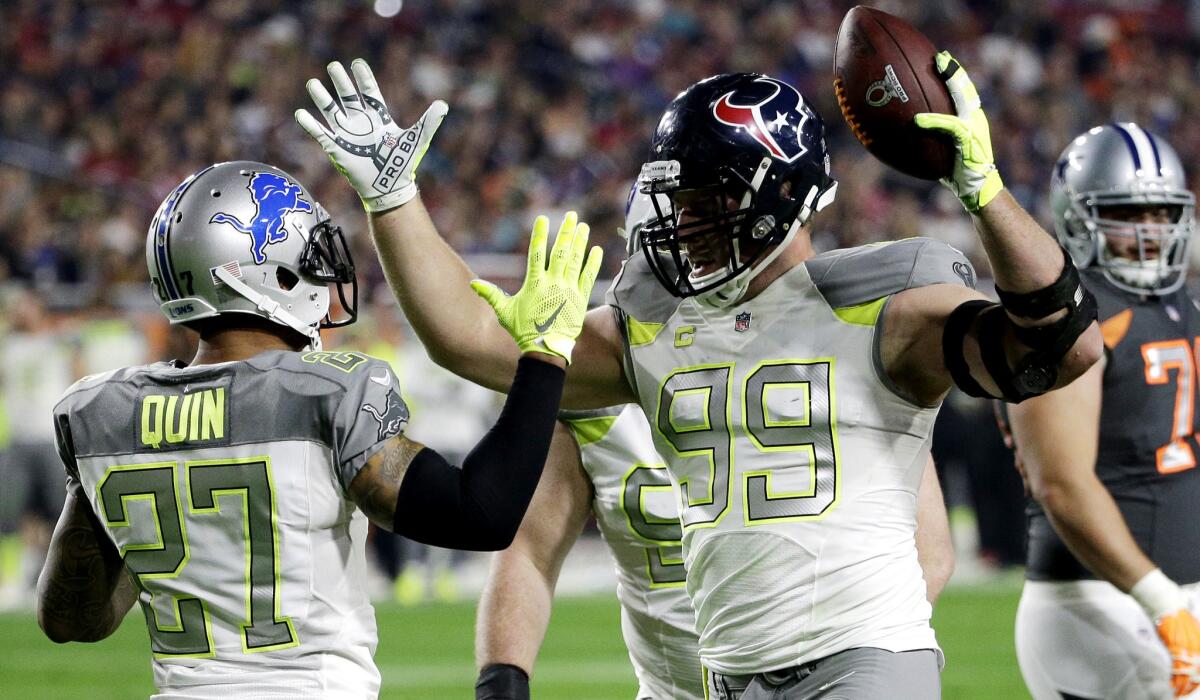 Texans defensive end J.J. Watt (99) is congratulated by Lions defensive back Glover Quin after intercepting a pass in the first half of the Pro Bowl on Sunday.