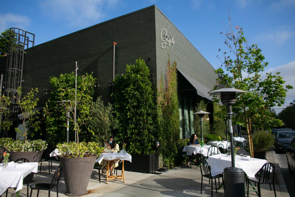 Tables and chairs alongside potted trees on a restaurant's outdoor patio