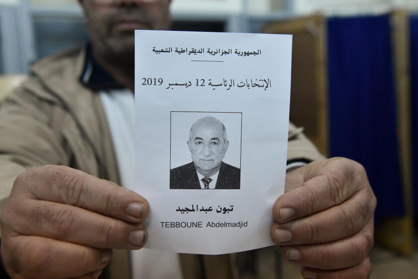 An election official displays a ballot paper of Algeria's presidential candidate Abdelmadjid Tebboune during the counting process in the capital Algiers on December 12, 2019. - Algeria held a tense presidential election meant to bring stability after a year of turmoil, but voting was marred as protesters stormed polling stations and staged mass rallies in the capital. (Photo by RYAD KRAMDI / AFP) (Photo by RYAD KRAMDI/AFP via Getty Images)