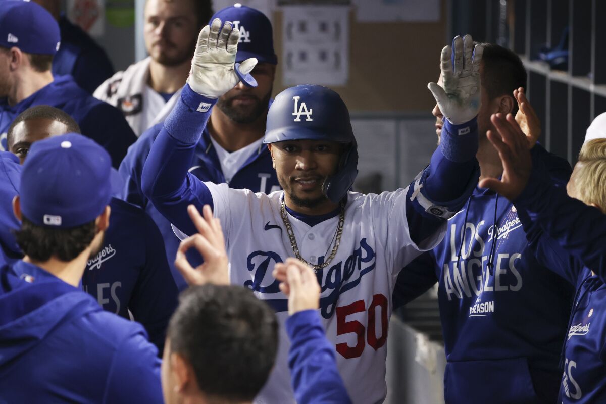 Dodgers outfielder Mookie Betts celebrates with teammates in the dugout.