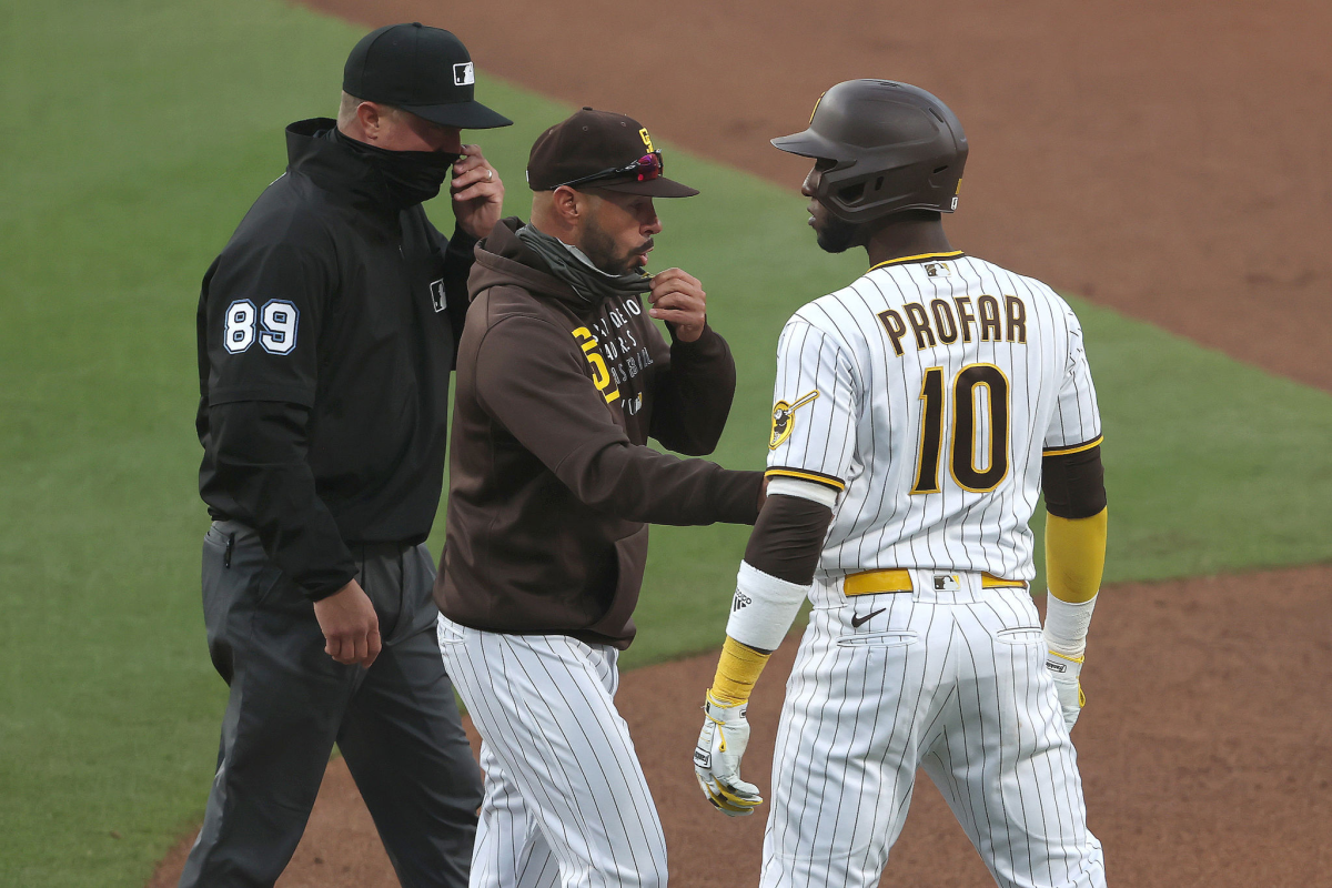 Padres manager Jayce Tingler, center, holds back Jurickson Profar as he stares at Dodgers pitcher Clayton Kershaw.