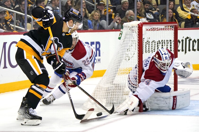Montreal Canadiens goaltender Jake Allen (34) knocks the puck off the stick of Pittsburgh Penguins' Jason Zucker, left, with Canadiens' Ryan Poehling (25) defending during the second period of an NHL hockey game in Pittsburgh, Saturday, Nov. 27, 2021. (AP Photo/Gene J. Puskar)