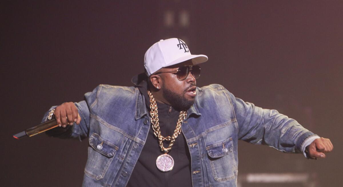 Big Boi in a jean jacket holding a microphone and rapping on stage