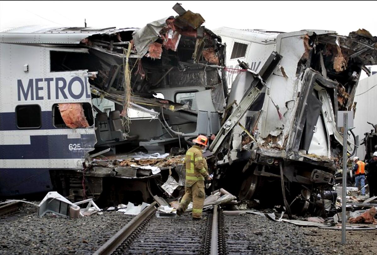 A firefighter stands on the tracks in front of the wreckage of a commuter train
