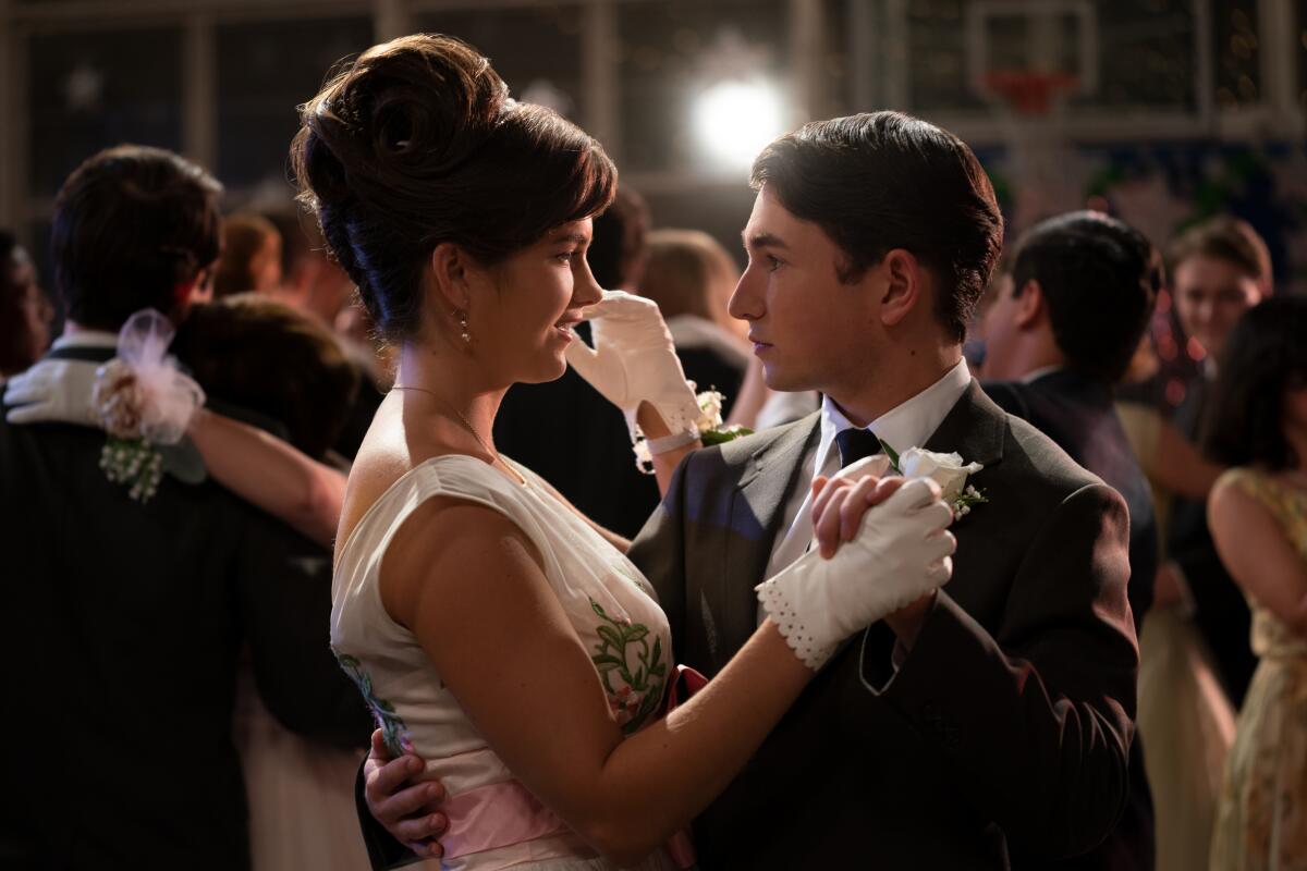 Chloe East in an updo and a dress dances with Gabriel LaBelle, who is in a suit, in the movie "The Fabelmans."