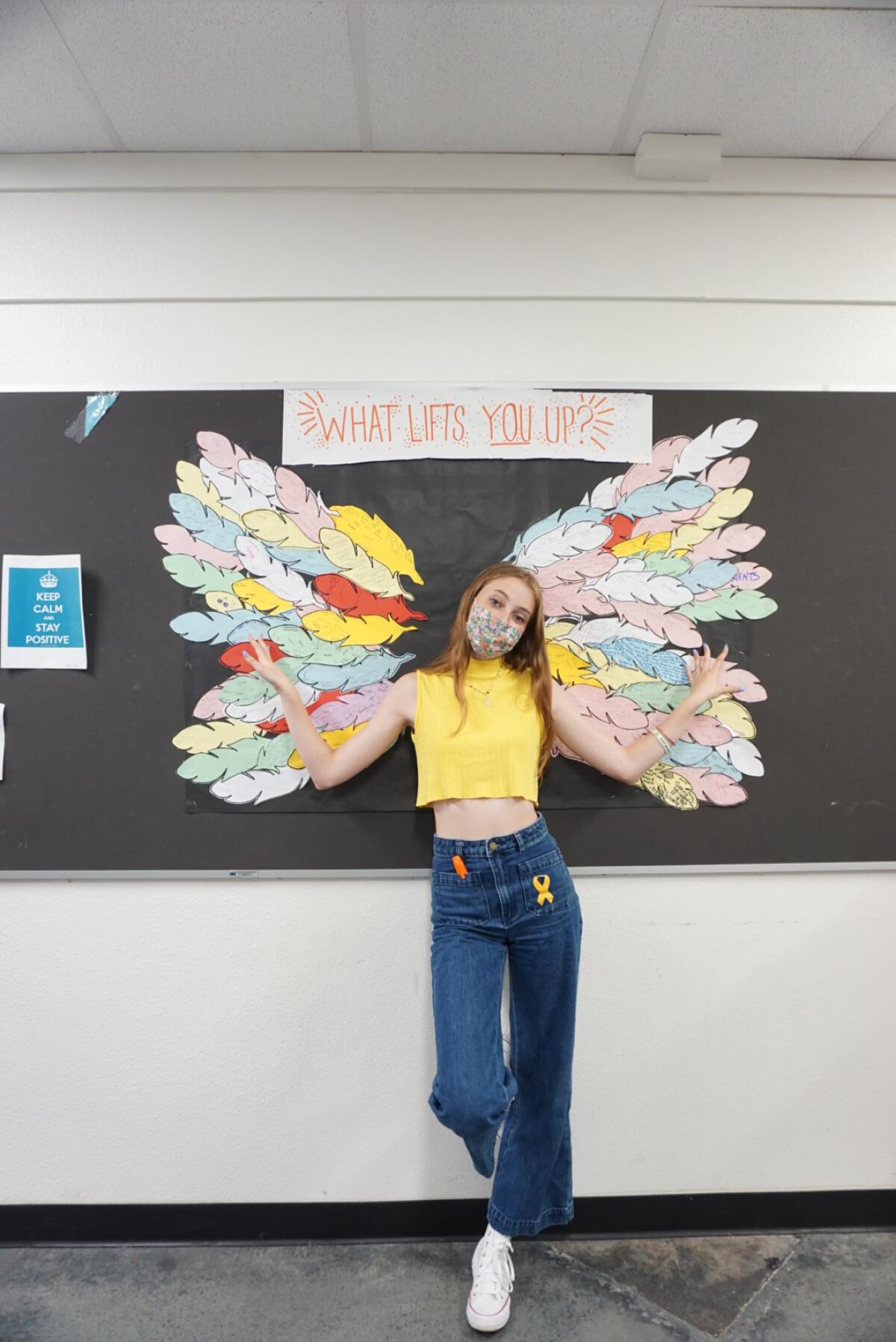 Senior Mirabel Hunt in front of the "What Lifts You Up?" wings