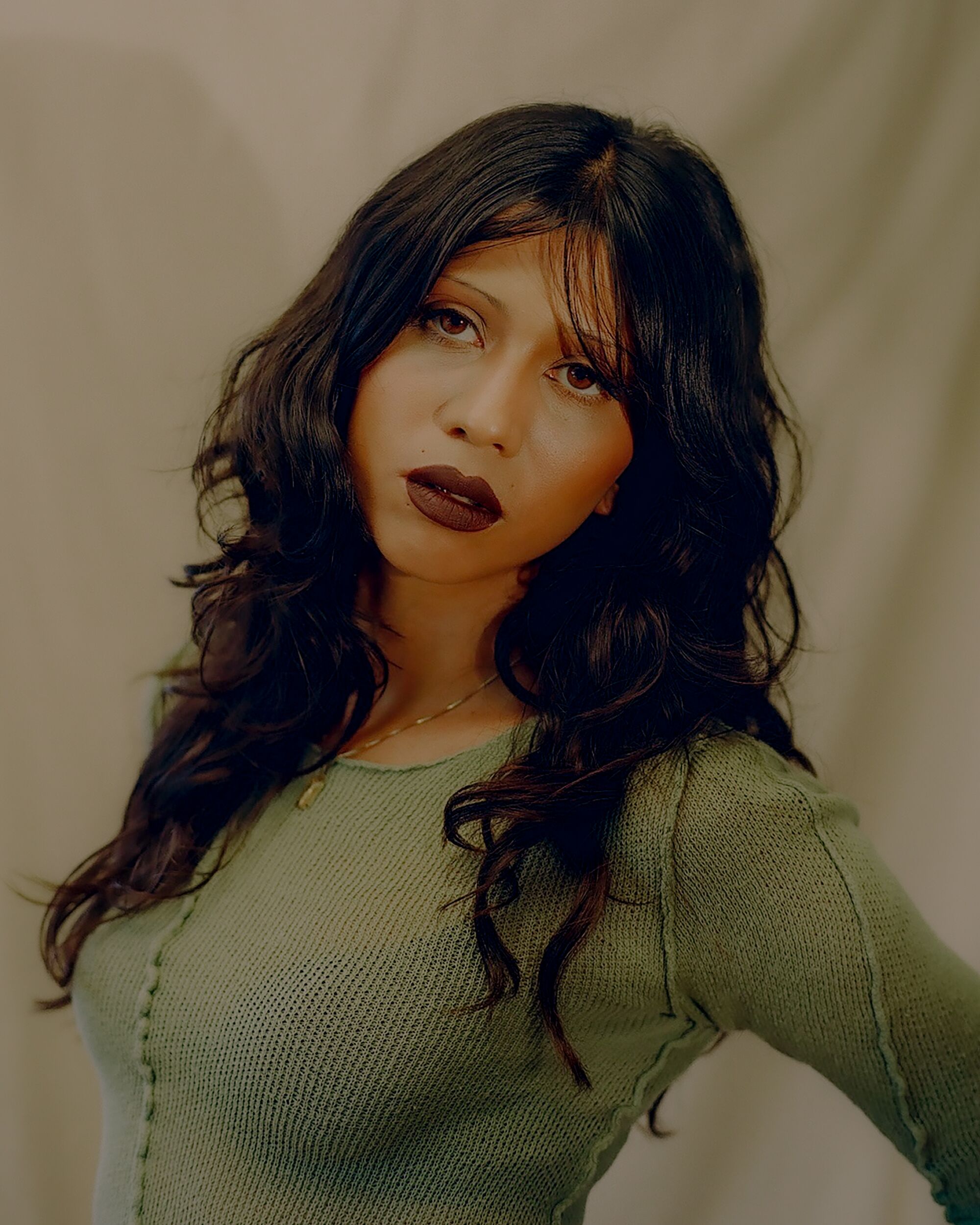 Tweezing is the self-care beauty routine for warped times 4 Model wearing green top looks at camera.