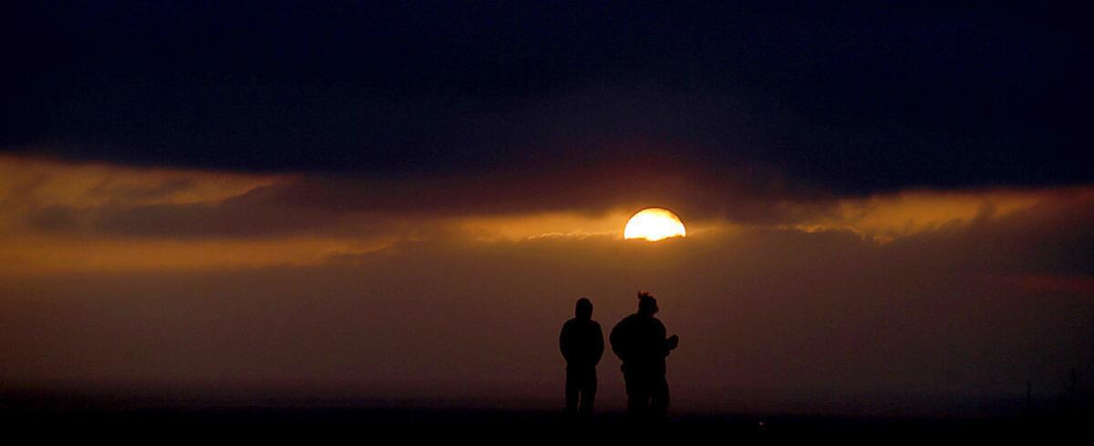 The setting sun casts a golden glow as the clouds of a cold front blow into Southern California on Wednesday.