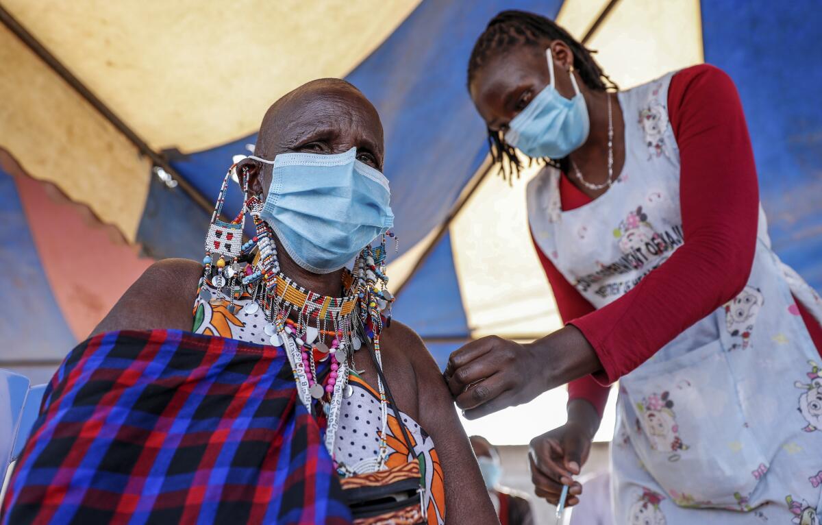 A woman wearing a mask is administered a vaccine