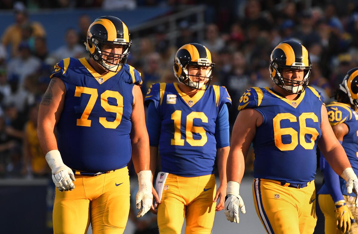 Rams tackle Rob Havenstein (79) stands with quarterback Jared Goff (16) and Austin Blythe at the Coliseum on Sunday.