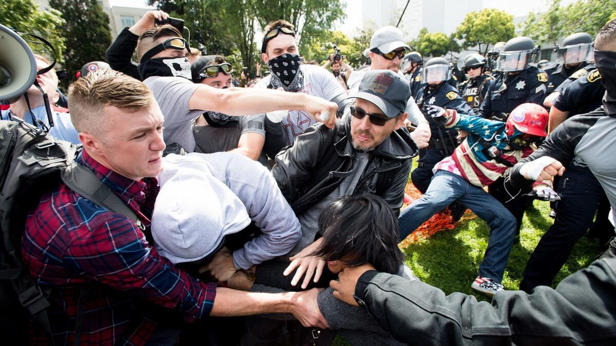 Robert Boman is shown punching a counter-protester in Berkeley while Aaron Eason, Michael Miselis and other members of the Rise Above Movement stand beside him.