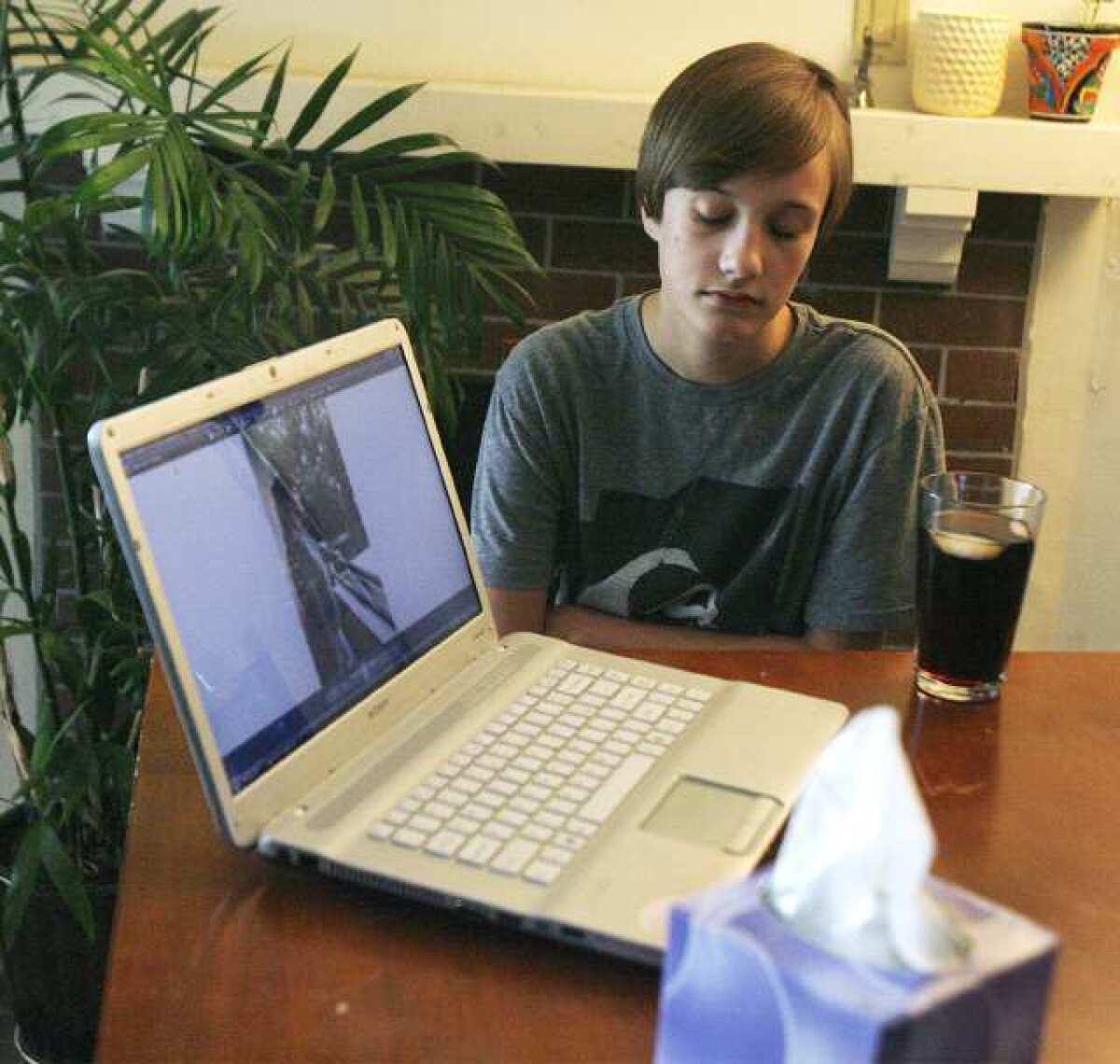 With a photo of his mom on a laptop, Brandon Holbrooks, 15, sits in his step-grandfather's apartment in Glendale. Brandon and his sister Ashley, 18, moved in with their step-grandfather after their mom died, possibly from an asthma attack, during the Christmas break. Her funeral is Saturday. Their father committed suicide three years ago. They are looking to the community for help with funeral and moving expenses.