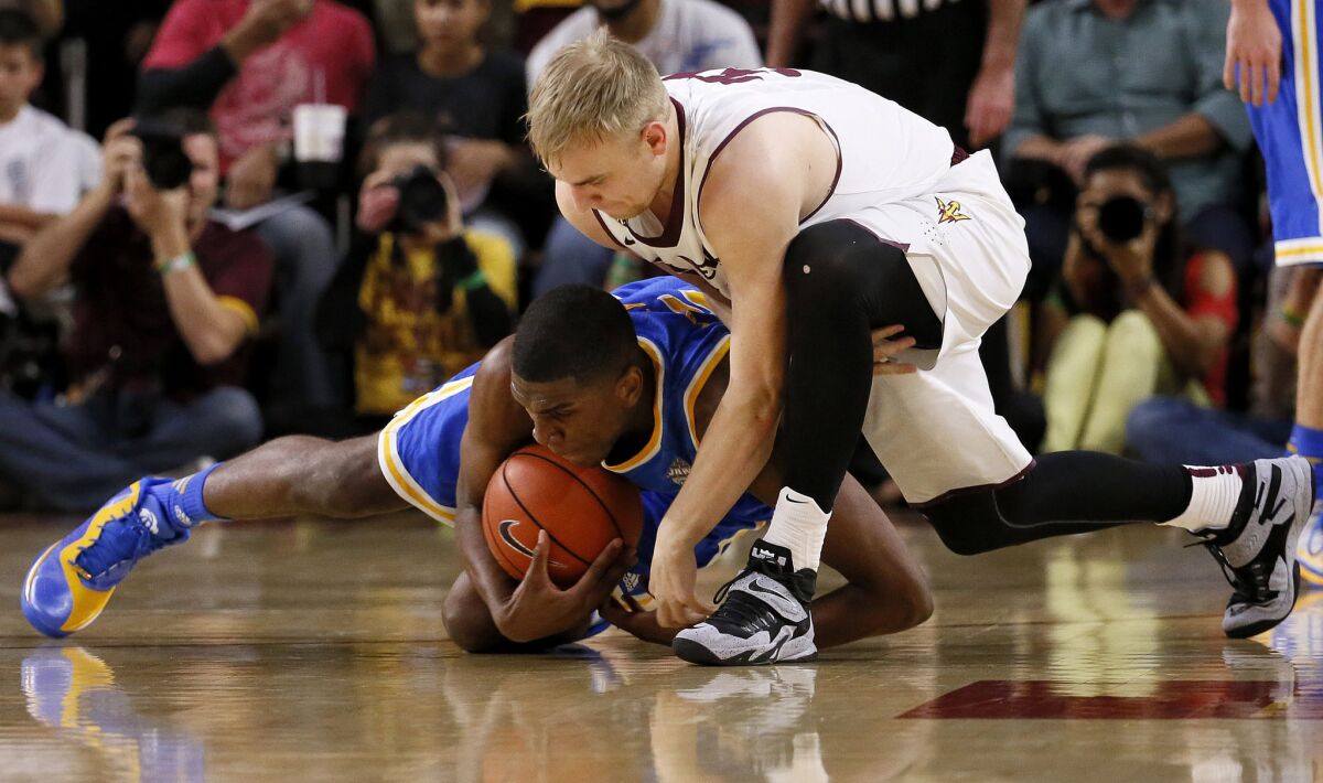 UCLA's Kevon Looney and Arizona State's Jonathan Gillig battle for a loose ball on the court on Wednesday.