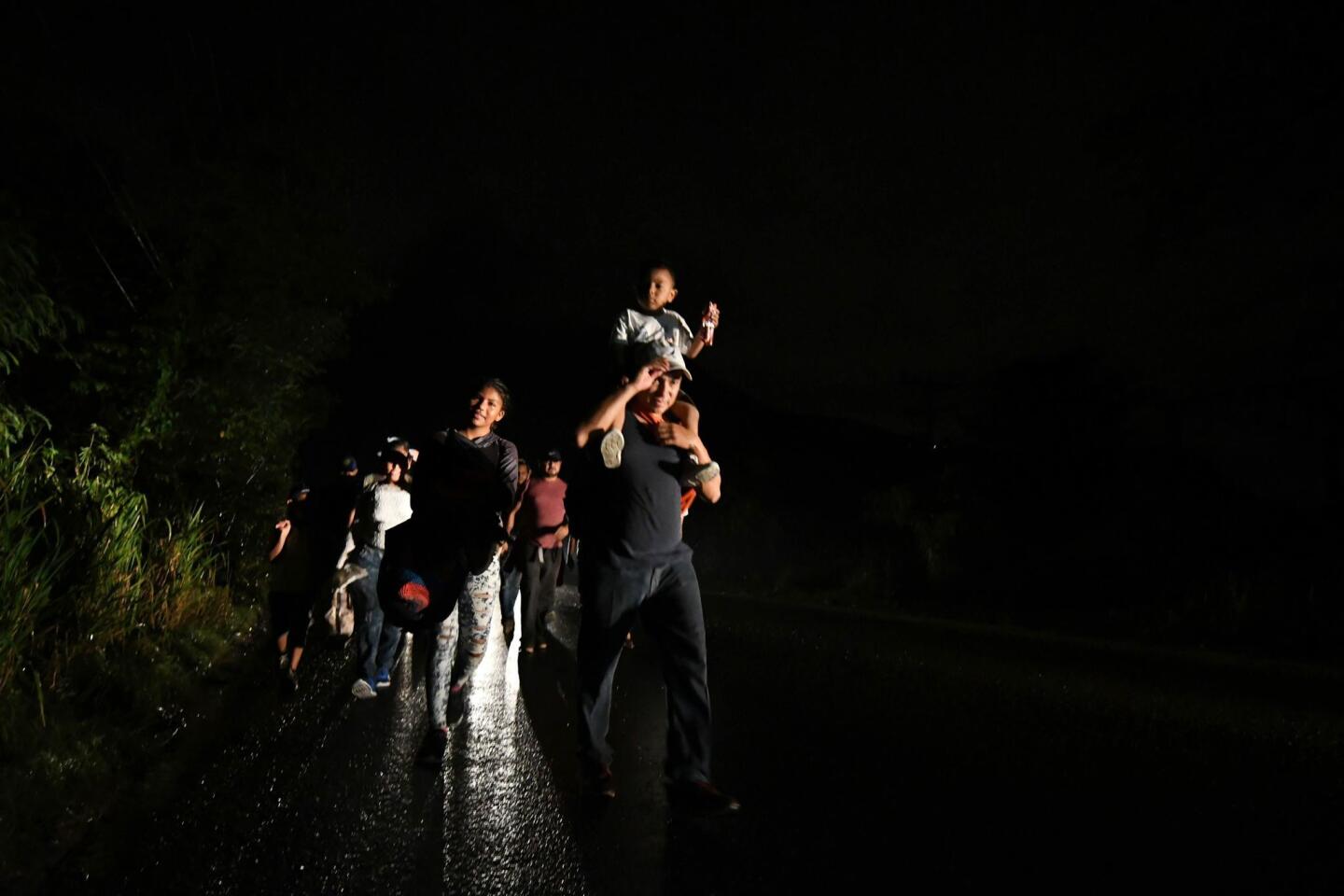 Un hombre lleva a un niño sobre sus hombros mientras los inmigrantes hondureños, parte de la caravana a los Estados Unidos, salen de San Pedro Sula, 180 km al norte de Tegucigalpa.