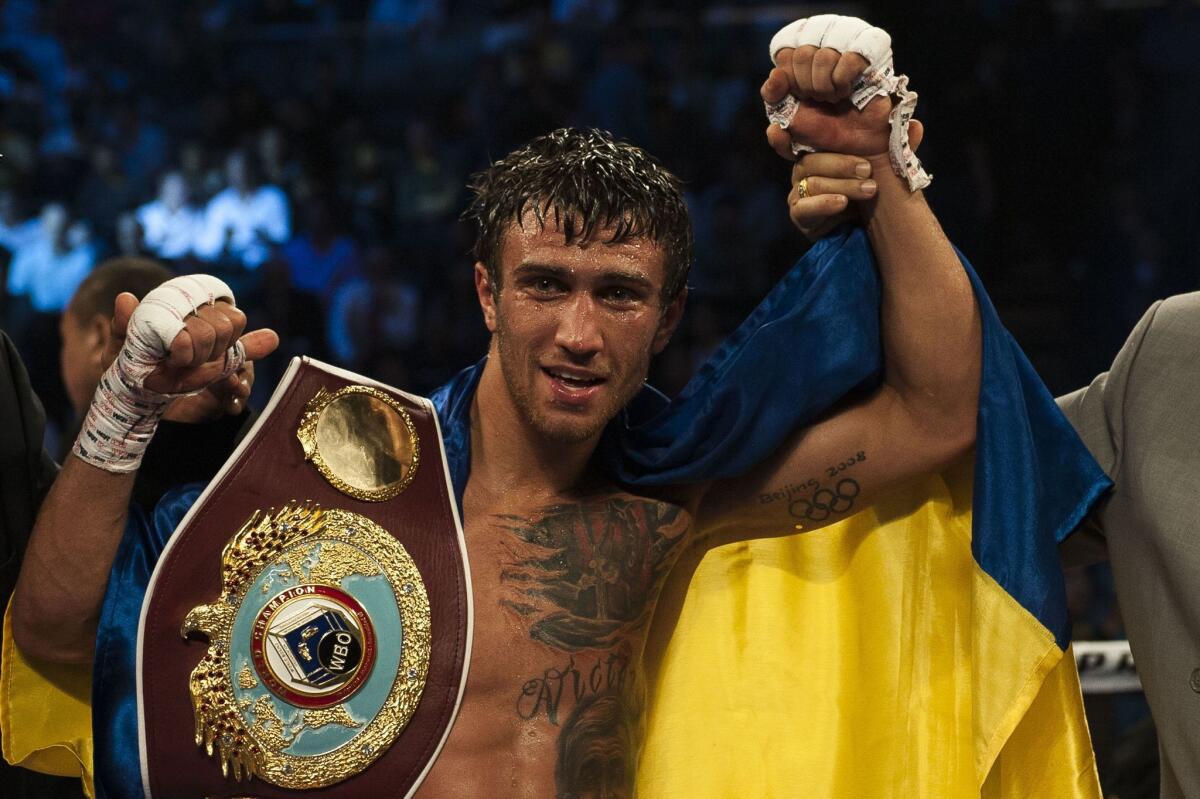Vasyl Lomachenko has his hand raised after his victory over Chonlatarn Piriyapinyo in their WBO featherweight title fight Nov. 23 in Macao.