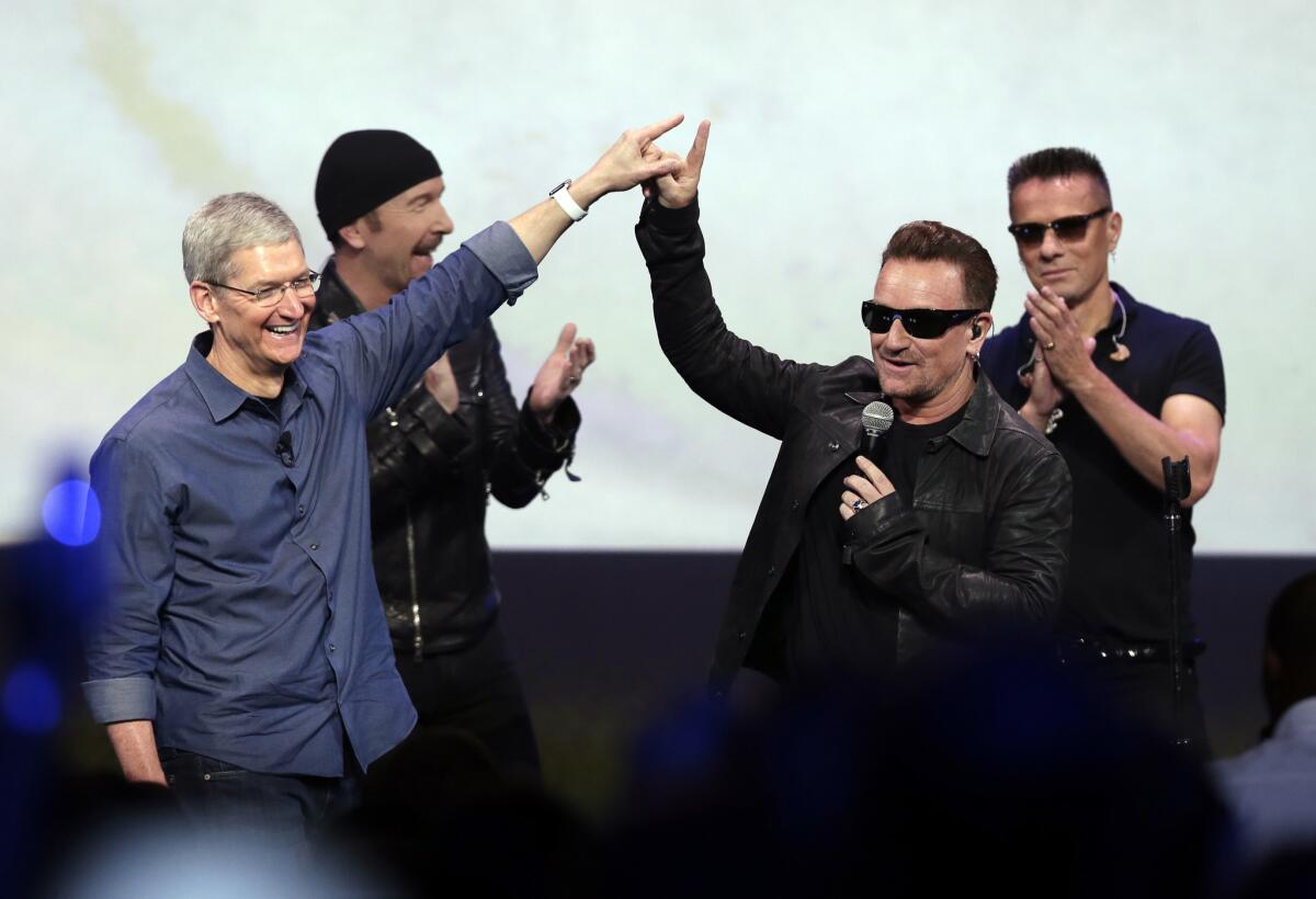 Apple CEO Tim Cook, left, greets Bono from the band U2 after they preformed at the end of the Apple event on Tuesday, Sept. 9, 2014.