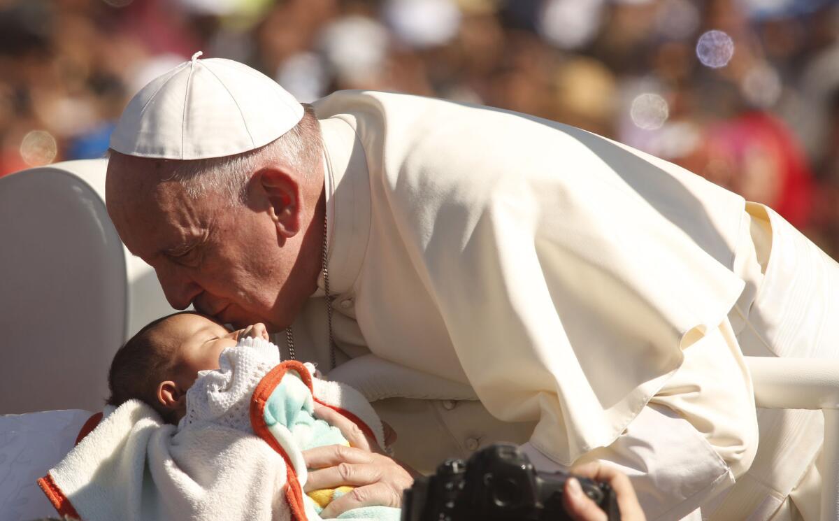 Pope Francis kisses a baby while riding through a crowd of pilgrims, many from indigenous communities surrounding San Cristobal de las Casas. The Mass included several Mayan languages.