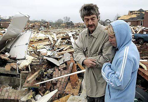 Mike Whitefield and his wife, Anita, look over the remains of a tornado-damaged house where Mike sought shelter by hiding in the crawl space with his son on Friday, in Gallatin, Tenn., a suburb of Nashville. Whitefield and his son were working at the house at the time of the storm.