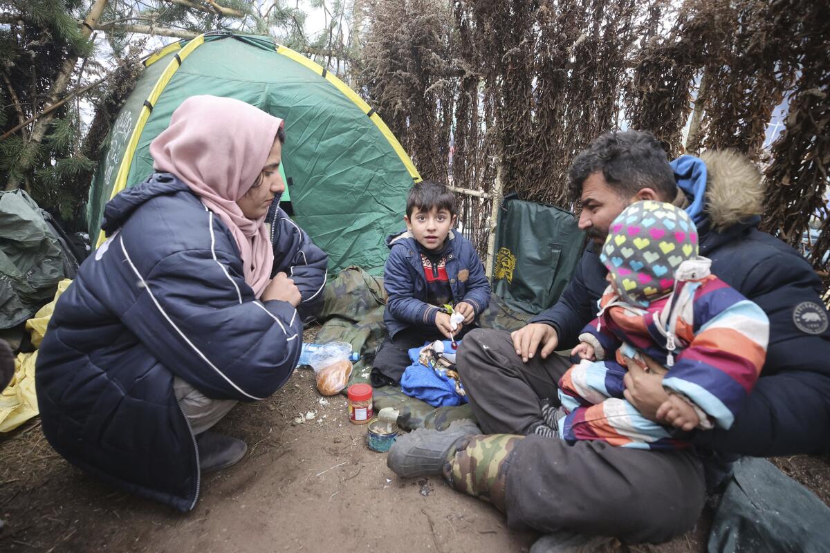 A migrant family eats at a tent camp at the Belarus-Poland border.