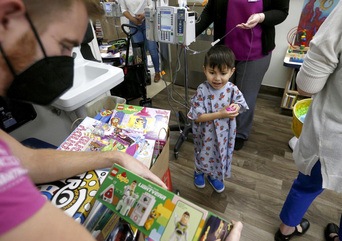 Randall Auna-Villa from Starlight Children's Foundation gives Aiden Ayala, 4, a Buzz Lightyear LEGO man Friday.